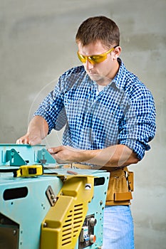 Young men adjusts woodworking mashine