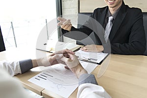 Young men are being interviewed by employers. The employer wears a black suit explaining the job application