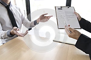 Young men are being interviewed by employers. The employer wears a black suit explaining the job application