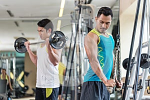 Young man exercising triceps pushdown next to his friend