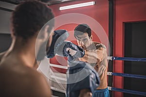 Young men fighting on a boxing ring and looking determined