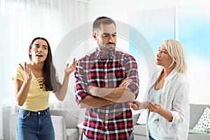 Young man having argument with wife and mother-in-law photo