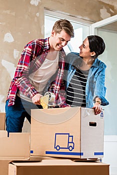 Young man and his girlfriend sealing a box while renovating their home