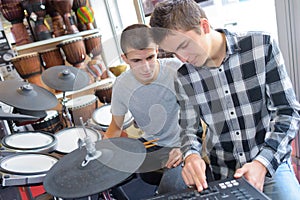 Young men looking at electronic drum machine