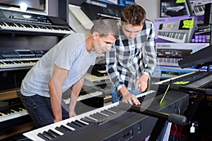 Young men looking at keyboards in musical shop