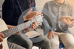 Young men play the guitar, praise God with music, and worship God together in a Christian family. Friendship is a Christian