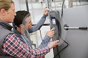 Young men in professional training controlling heat pump