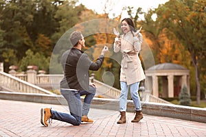 Young man proposing to his beloved in autumn park