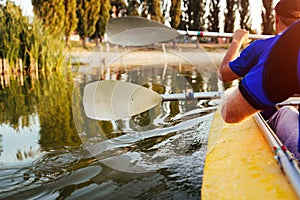 Young men rowing kayak on river at sunset. Couple of friends having fun canoeing in summer. Closeup of paddles