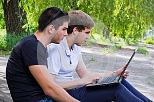 Young men sitting on the ground using laptop