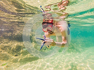 Young men snorkeling exploring underwater coral reef landscape background in the deep blue ocean with colorful fish and