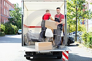 Young Men Stacking The Cardboard Boxes In Moving Truck