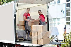 Young Men Stacking The Cardboard Boxes In Moving Truck