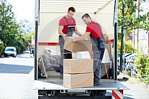 Young Men Stacking The Cardboard Boxes In Moving Truck