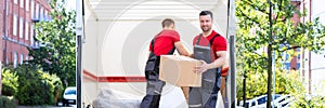 Young Men Stacking The Cardboard Boxes In Moving Truck