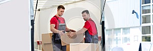 Young Men Stacking The Cardboard Boxes In Moving Truck