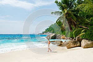 Young men in swimshort on a white tropical beach with palm trees Petite Anse beach Mahe Seychelles