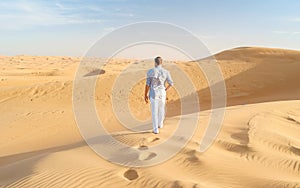 Young men walking in the desert of Dubai, Sand dunes of Dubai United Arab Emirates
