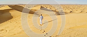 Young men walking in the desert of Dubai, Sand dunes of Dubai United Arab Emirates