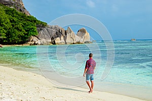 Young men walking at a white tropical beach Anse Source d'Argent beach La Digue Seychelles Islands