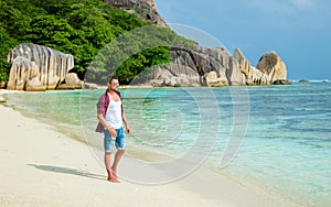 Young men walking at a white tropical beach Anse Source d'Argent beach La Digue Seychelles Islands