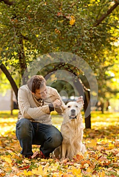 A young men walks in autumn park with a Labrador. Guy playfully