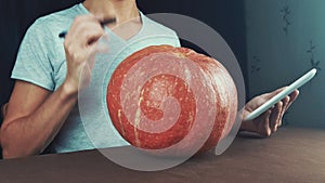 Young men in white t-shirt use tablet computer and examine pumpkin in front of him 4k