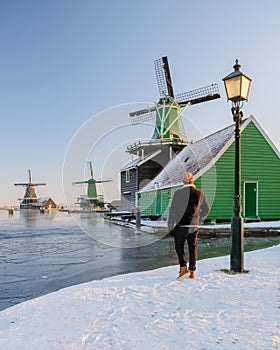 young men in winter visit the Zaanse Schans windmill village during winter with snow