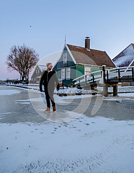 young men in winter visit the Zaanse Schans windmill village during winter with snow