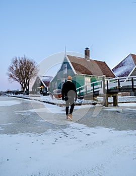 young men in winter visit the Zaanse Schans windmill village during winter with snow