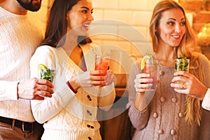 Young men and women drinking cocktail at party