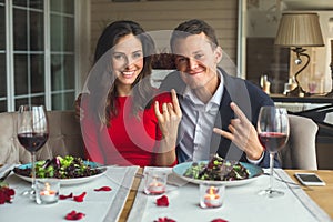 Young couple having romantic dinner in the restaurant sitting together taking photos grimase