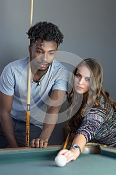 Young men and women in poolroom playing pool team players portrait billiards table nightlife activity