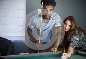 Young men and women in poolroom playing pool team players portrait billiards table nightlife activity