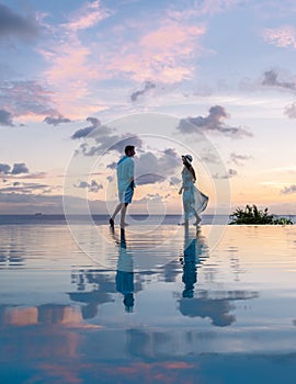Young men and women watching sunset with reflection in the infinity pool at Saint Lucia Caribean