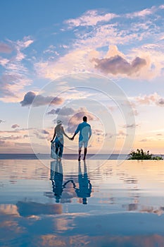 Young men and women watching sunset with reflection in the infinity pool at Saint Lucia Caribean