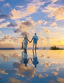 Young men and women watching sunset with reflection in the infinity pool at Saint Lucia Caribean