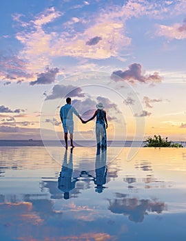 Young men and women watching sunset with reflection in the infinity pool at Saint Lucia Caribean