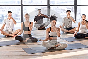 Young men and women in yoga studio practicing alternate nostril breathing exercises