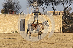 A Young Mexican Charro Cowboy Rounds Up A Herd of Horses Running Through The Field On A Mexican Ranch At Sunrise