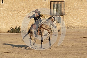 A Young Mexican Charro Cowboy Rounds Up A Herd of Horses Running Through The Field On A Mexican Ranch At Sunrise photo