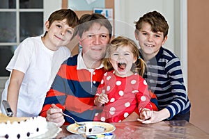 Young middle-aged father with cute little toddler girl daughter and two kids boys sons. Lovely children and dad eating