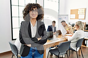 Young middle east businesswoman smiling happy standing with arms crossed gesture at the office during business meeting