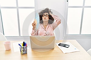 Young middle east businesswoman using hand fan at the office