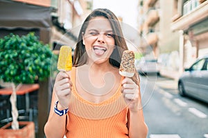 Young middle east girl bitting tongue and winking holding ice cream at the city