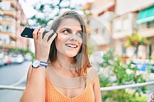 Young middle east girl smiling happy listening audio message using smartphone at the city