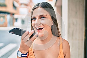 Young middle east girl smiling happy sending voice message using smartphone at the city