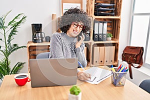 Young middle east woman business worker talking on smartphone write on notebook at office