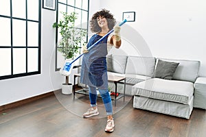 Young middle east woman cleaning and using mop as a guitar at home