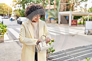 Young middle east woman excutive smiling confident holding handbag at street